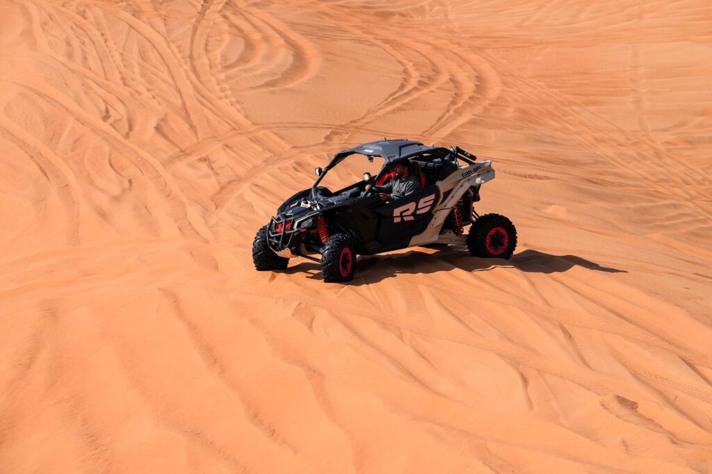 Single driver in buggy climbing steep sand dune Dubai