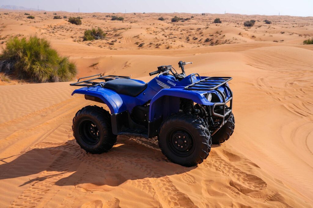 Quad biking trail through wide open red dunes Dubai
