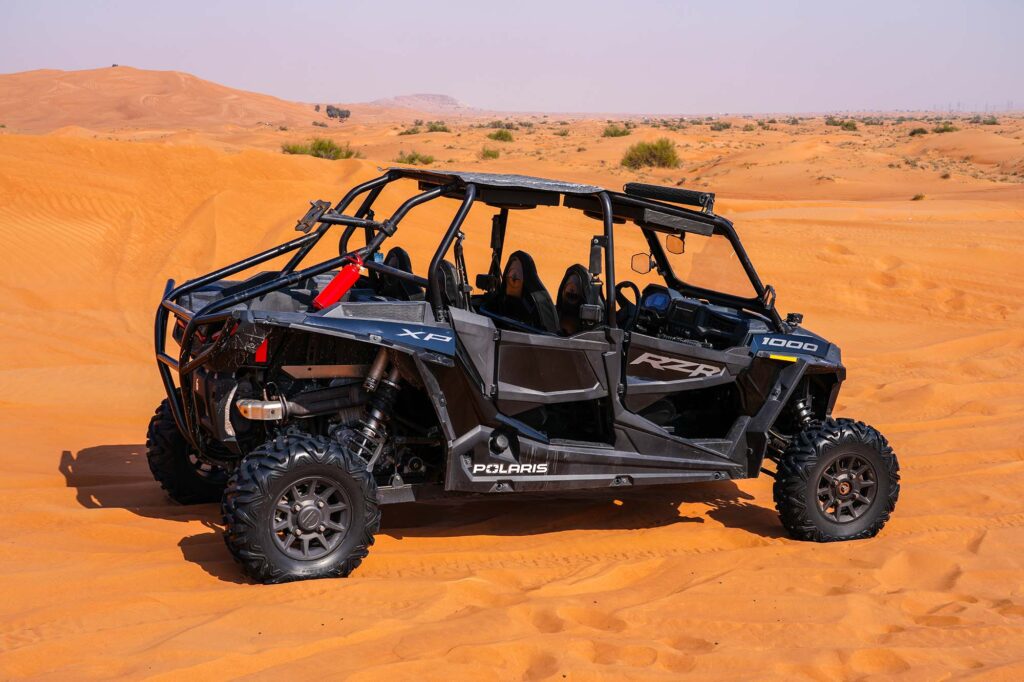 Golden hour buggy driving through red sand dunes Dubai